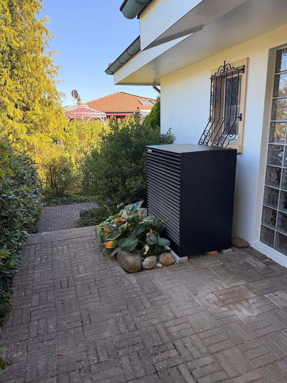 Pompa di calore installata discretamente accanto a una casa con giardino